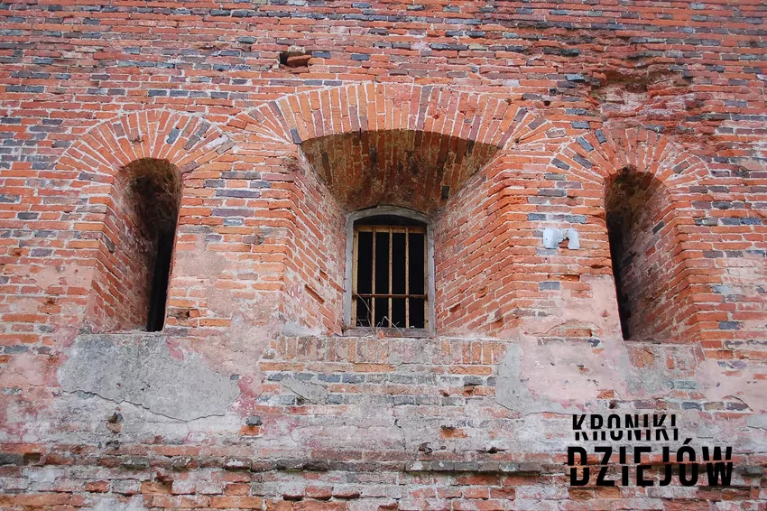 Fragment muru Reduty Napoleona – jeden z najstarszych zachowanych budynków twierdzy, fot. domena publiczna, lic. CC BY-SA 3.0 Fragment muru Reduty Napoleona, a także opis bitew z Twierdzą Modlin w tle