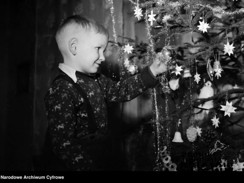 Chłopiec oglądający bombki na choince, fot. domena publiczna/Narodowe Archiwum Cyfrowe Chłopiec przy choince
